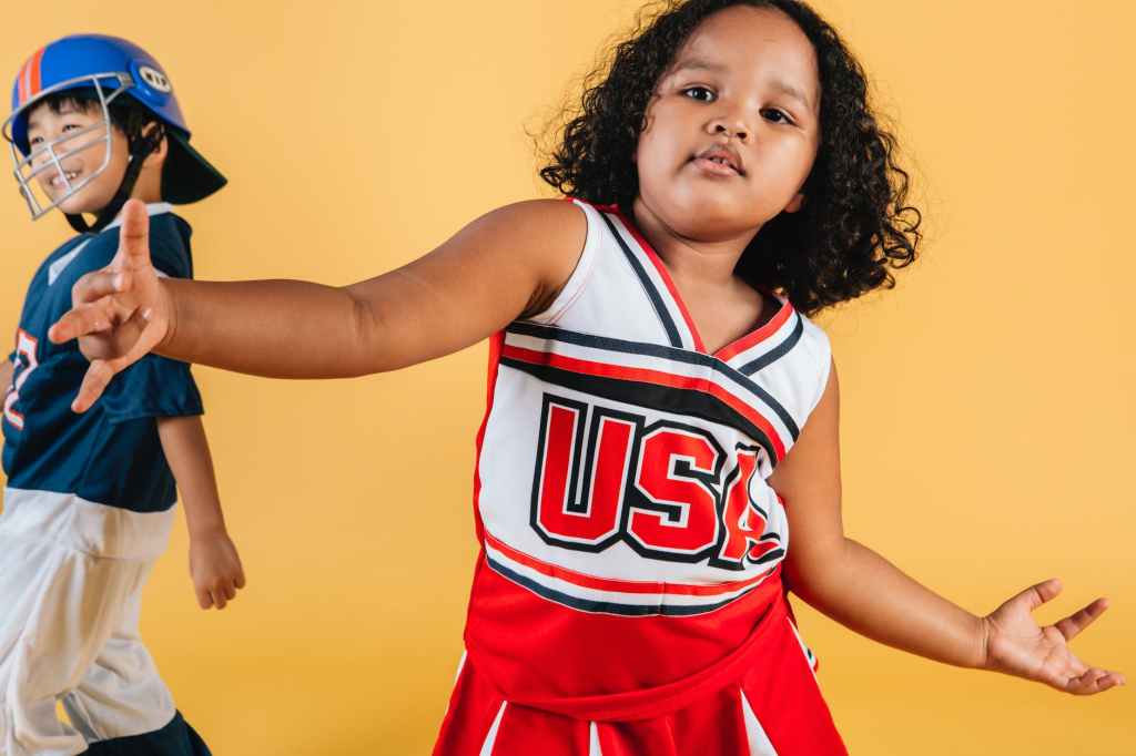 black cheerleader little girl near asian boy in football player costume