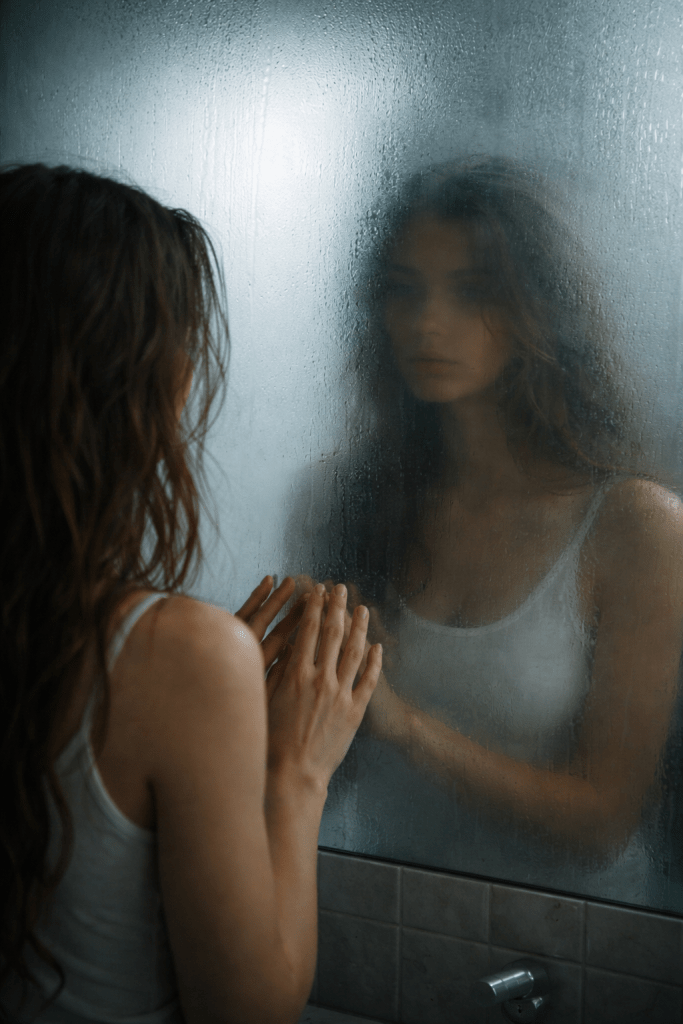 woman looking at reflection in a foggy mirror
